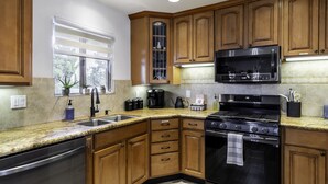 A kitchen with wooden cabinets, a stainless steel dishwasher, a microwave, a stove, and a sink.