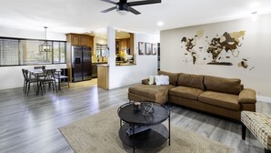 A modern living room with a sectional sofa, a coffee table, and a dining area with chairs and a table.