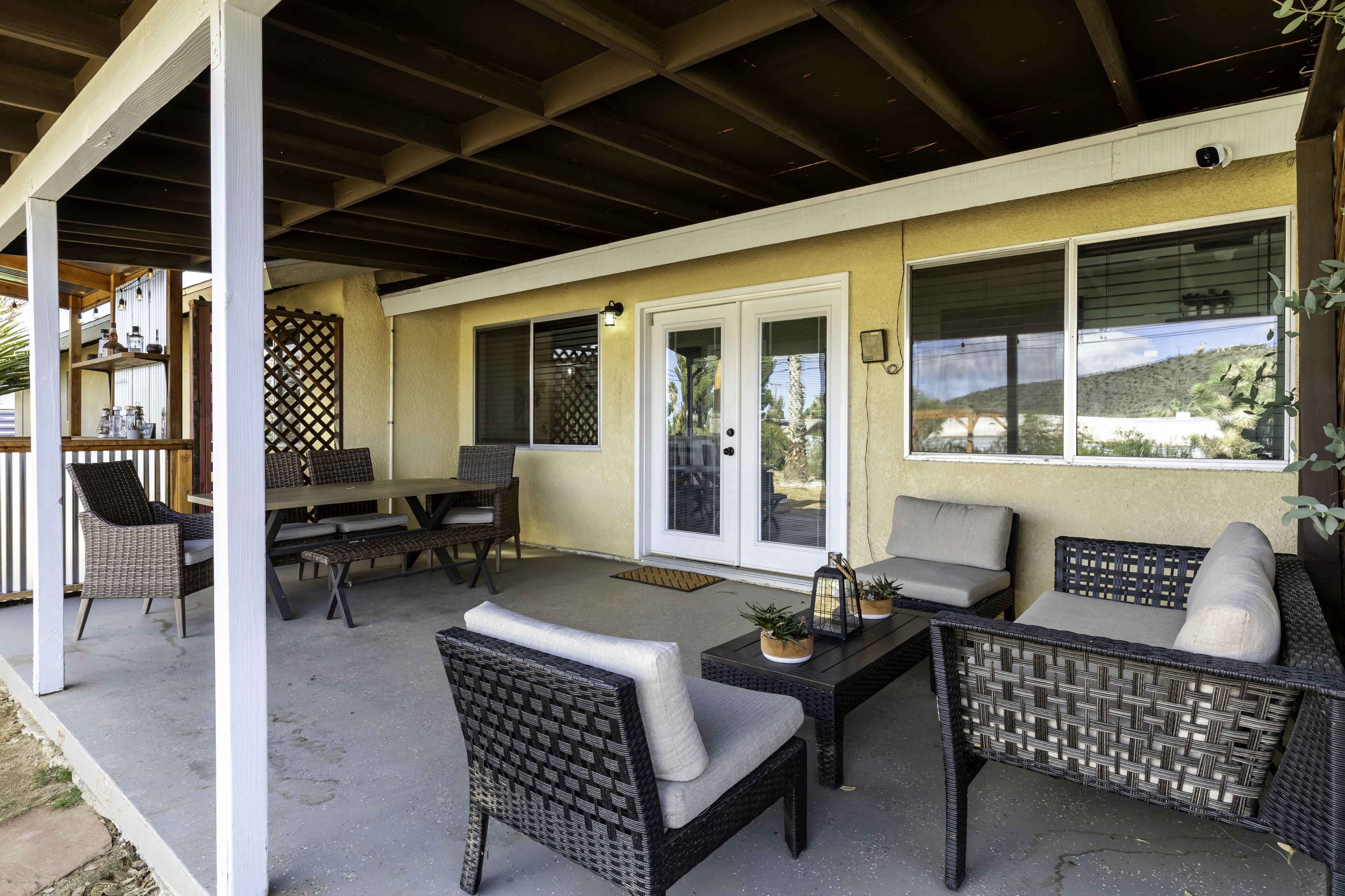 An outdoor patio with wicker furniture, a table, and a bench.