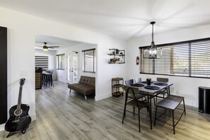 A spacious living area with a dining table, chairs, a sofa, and a guitar. - Sky Harbor House - Centrally Located W/hot Tub 3 Bedroom Home by RedAwning (Yucca Valley)