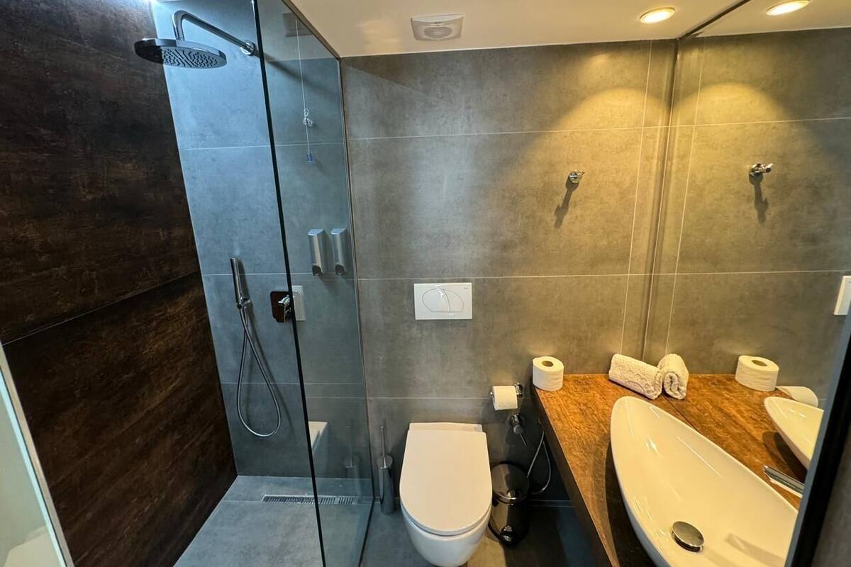 Ein modernes Badezimmer mit einer Duschkabine, einer Toilette und einem Waschbecken mit Holzabdeckung.