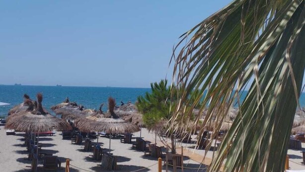 A beachside resort with thatched umbrellas, lounge chairs, and a view of the ocean. - Sea Side (Durrës)