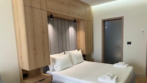 A modern bedroom with a large bed, wooden headboard, and a nightstand with drawers. - Sea Side (Durrës)