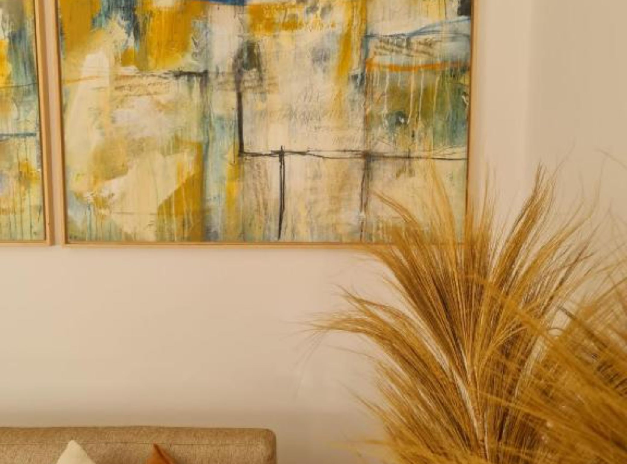 Two abstract paintings with a warm color palette on a plain wall.