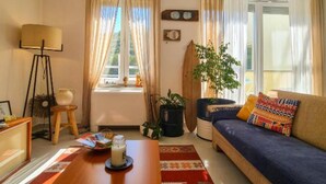 Un salon chaleureux avec un canapé, une table basse sur laquelle est posée une bougie, une lampe et une fenêtre avec des rideaux.