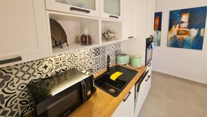 Une cuisine moderne avec des meubles blancs, un crédence à motifs, un grille-pain, une bouilloire et un évier.