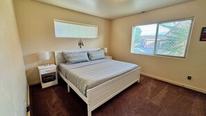 A bedroom with a bed, nightstands, a window, and a door. - Pet-Friendly I Rim Village I Garage I Pool & Hot Tub I Trailer Parking (Moab)