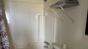 A bathroom with a white toilet, a bathtub, a shower, and a sink.