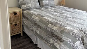 A bedroom with a bed, two bedside tables, a lamp, and a door.