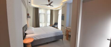 A modern hotel room with a large bed, a desk, and a chair.