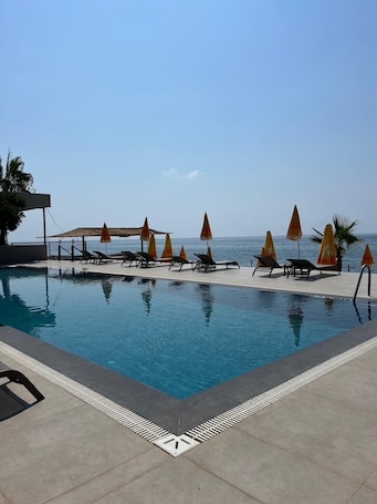 Una piscina al aire libre, sombrillas, sillones reclinables de piscina