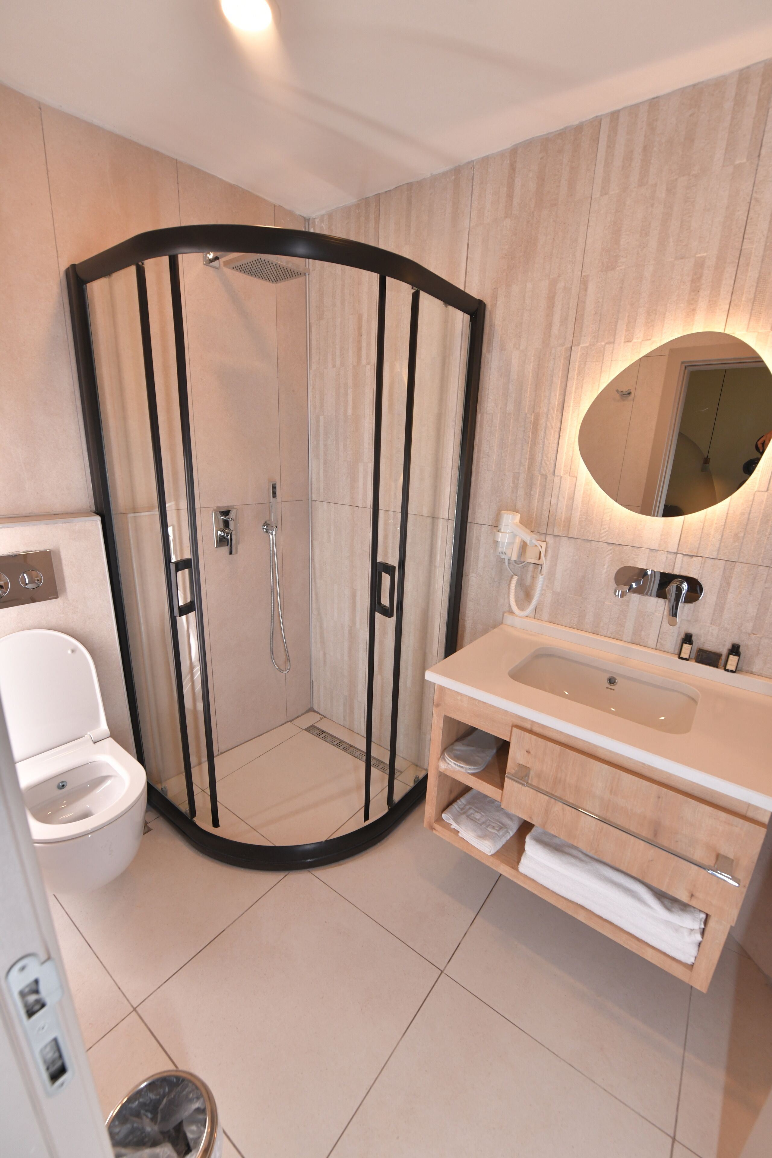 Une salle de bain moderne avec une douche à parois de verre, un lavabo avec un miroir et des toilettes.