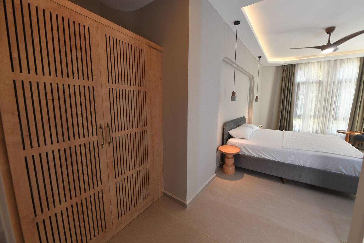 Een slaapkamer met een bed, nachtkastje en een houten garderobe.