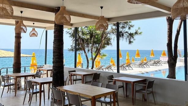 Ein Restaurant mit Blick auf den Pool, ausgestattet mit Korbtreleuchtern, Holztischen und -stühlen.