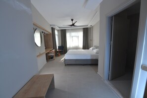 A modern hotel room with a large bed, a ceiling fan, a desk, and a chair. - Casalita Hotel (Erdemli)