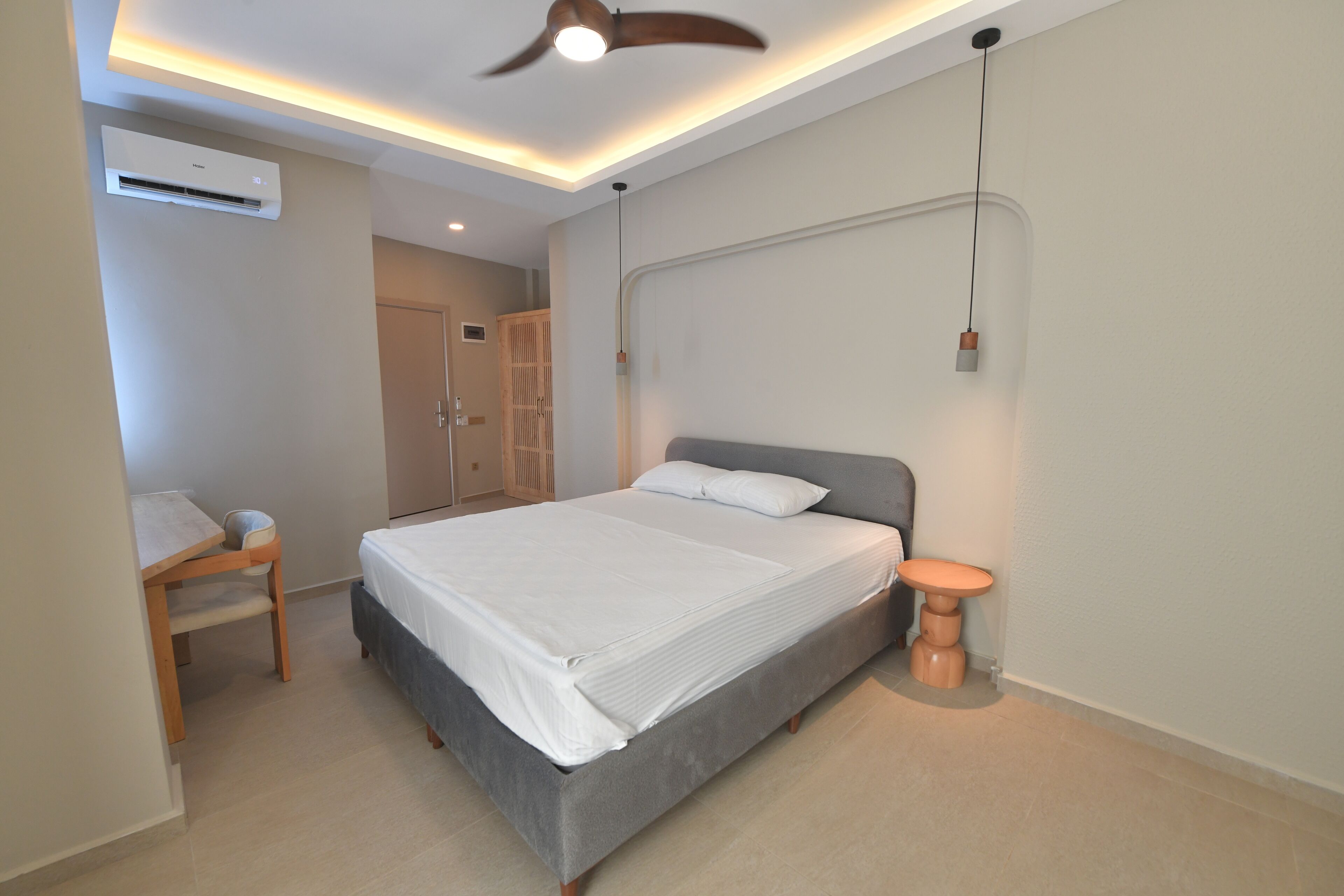 A modern bedroom with a bed, bedside table, and a desk.