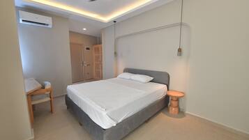 A modern bedroom with a bed, bedside table, and a desk.