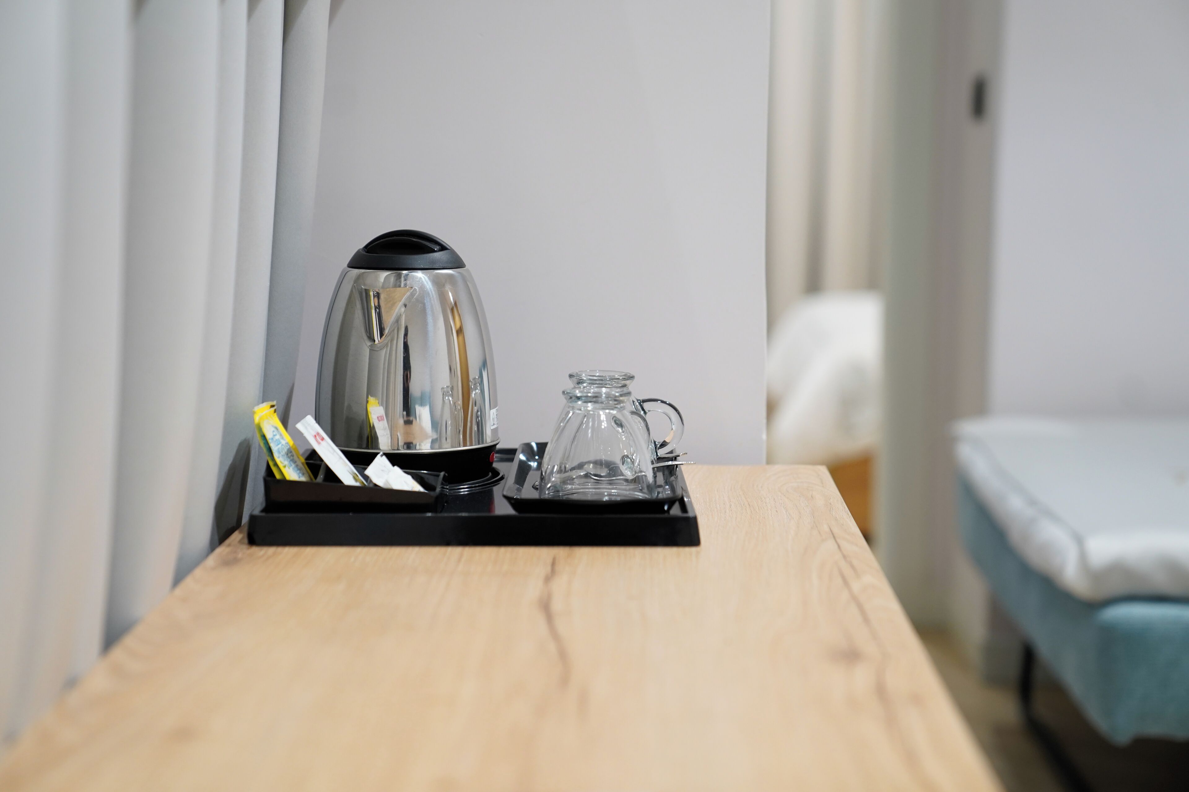 A wooden table with a coffee maker, a glass carafe, and a tray with some items.