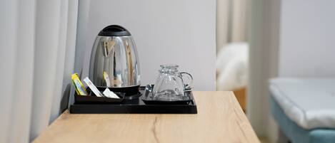 A wooden table with a coffee maker, a glass carafe, and a tray with some items.