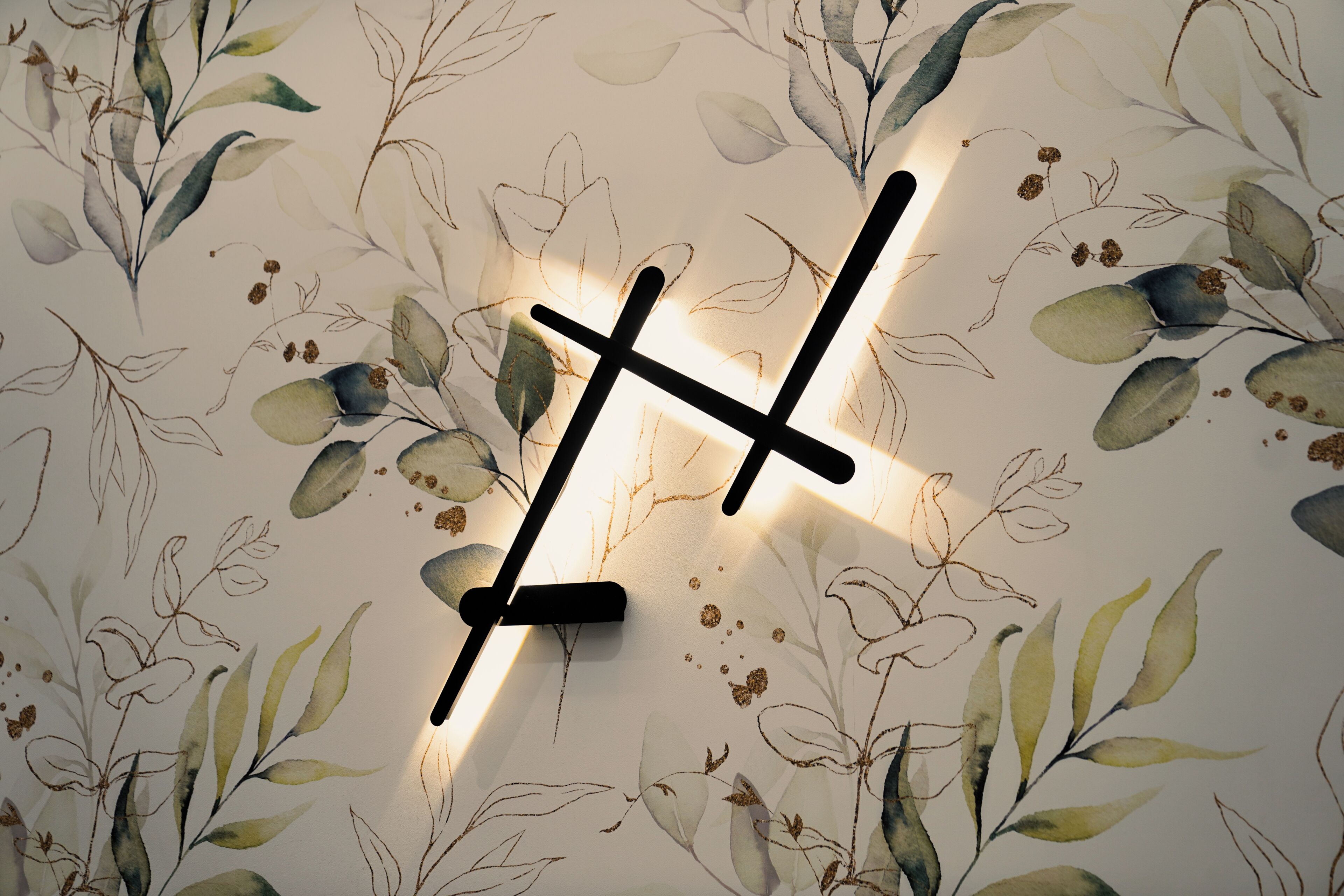A wall with a floral pattern and a modern light fixture.