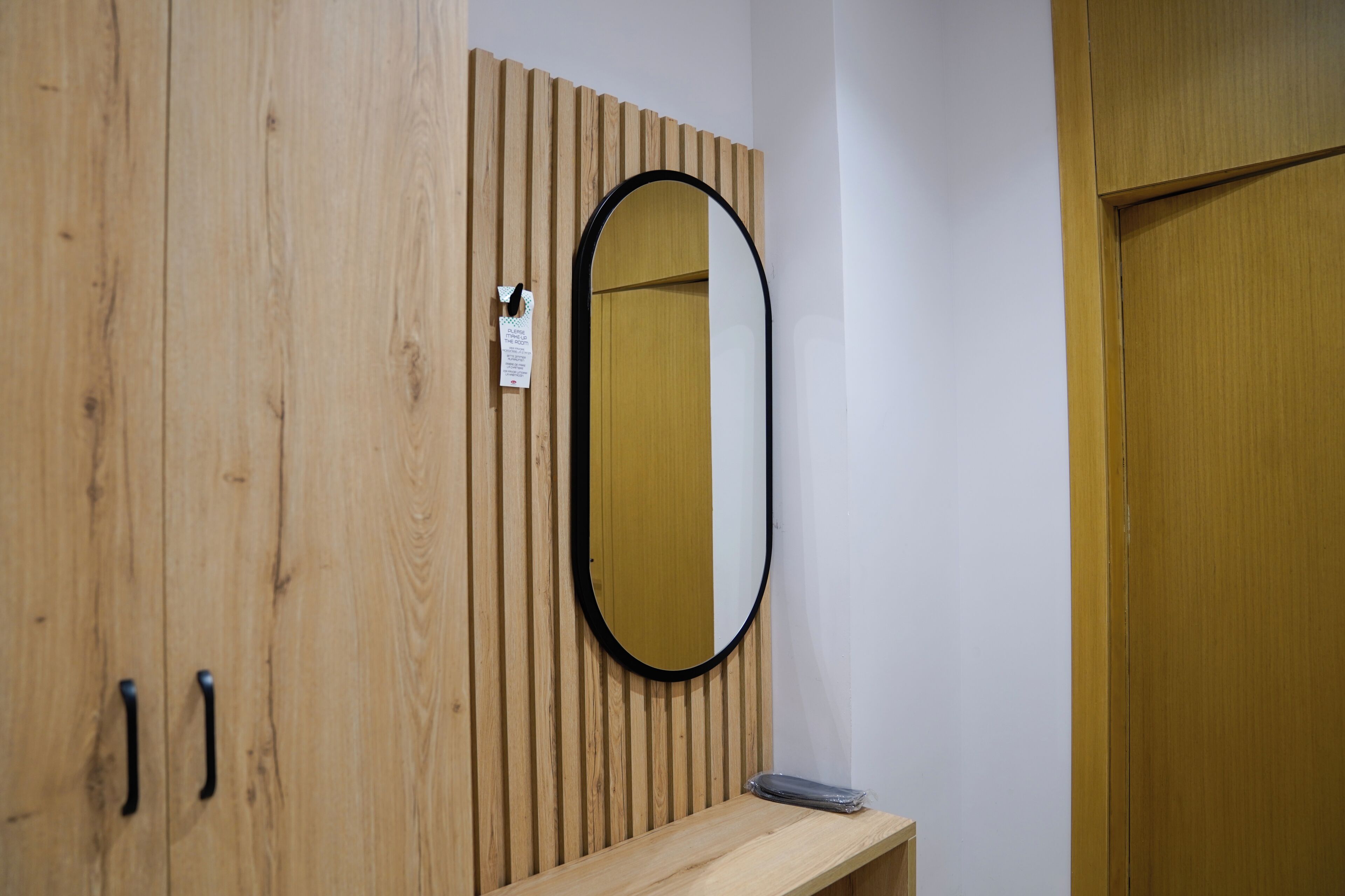 Un armario de madera con espejo, un estante pequeño y una puerta.