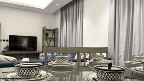 Un coin repas avec une table en verre dressée pour quatre personnes, agrémentée de bols et d’assiettes aux motifs noirs et blancs.