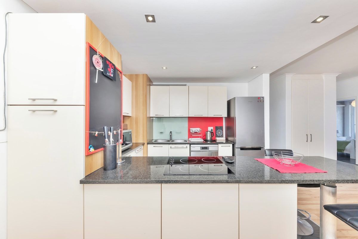 A modern kitchen with white cabinets, a granite countertop, and stainless steel appliances.