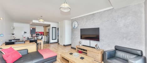 Un salon moderne avec un canapé, une table basse et un téléviseur.
