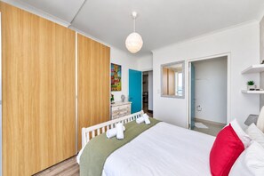 A hotel room with a bed, a wardrobe, a dresser, a mirror, and a view of the sea.