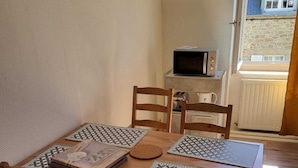 Zona pranzo con tavolo e sedie in legno, un forno a microonde e vista sull'esterno.