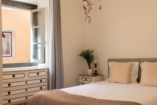 A bedroom with a bed, a dresser, a nightstand, a window, and a wall decoration. - Sintra Historic Centre Romantism Capital (Sintra)