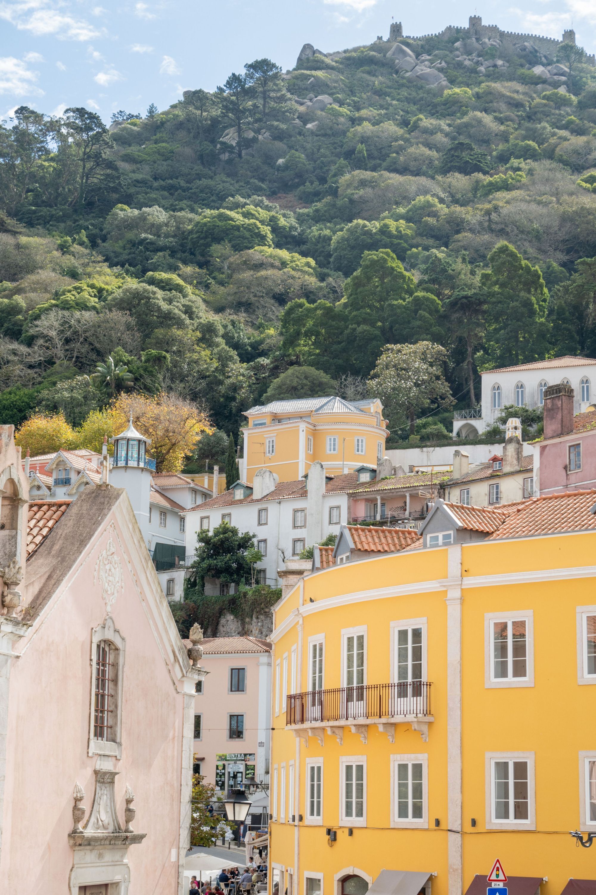 A hillside town with buildings, including a yellow building with a balcony.
