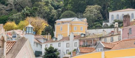A hillside town with buildings, including a yellow building with a balcony.