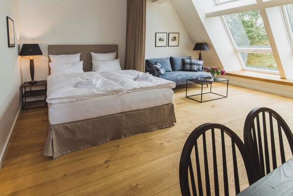 A bedroom with a bed, a sofa, a coffee table, and a window with a view. - Gut Damp (Damp)