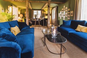 A room with two blue sofas, a small table with a candle, and a wall with framed pictures.