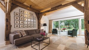 A living room with a wooden ceiling, a sofa, a coffee table, and a wall of framed pictures. - Gut Damp (Damp)