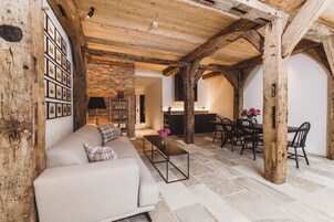 Un interno rustico con travi a vista in legno, pavimento in pietra, un divano, un tavolo da pranzo con sedie e un angolo cottura.