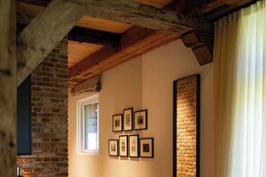 A hallway with exposed wooden beams, a brick wall, and framed pictures on the wall. - Gut Damp (Damp)
