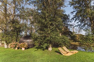 A garden with a wooden bench, a pond, and a wooden structure.