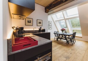Une cuisine moderne avec un coin repas, de grandes fenêtres et une vue sur l’extérieur.