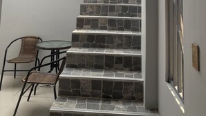 A staircase with stone steps leading to a balcony, a glass table with chairs, and a door with a metal frame. - Hotel Royal Mancora (Máncora)