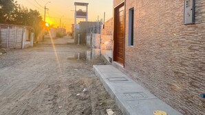 A narrow alleyway with a brick building on the right, a wooden structure on the left, and a metal gate in the center. - Hotel Royal Mancora (Máncora)
