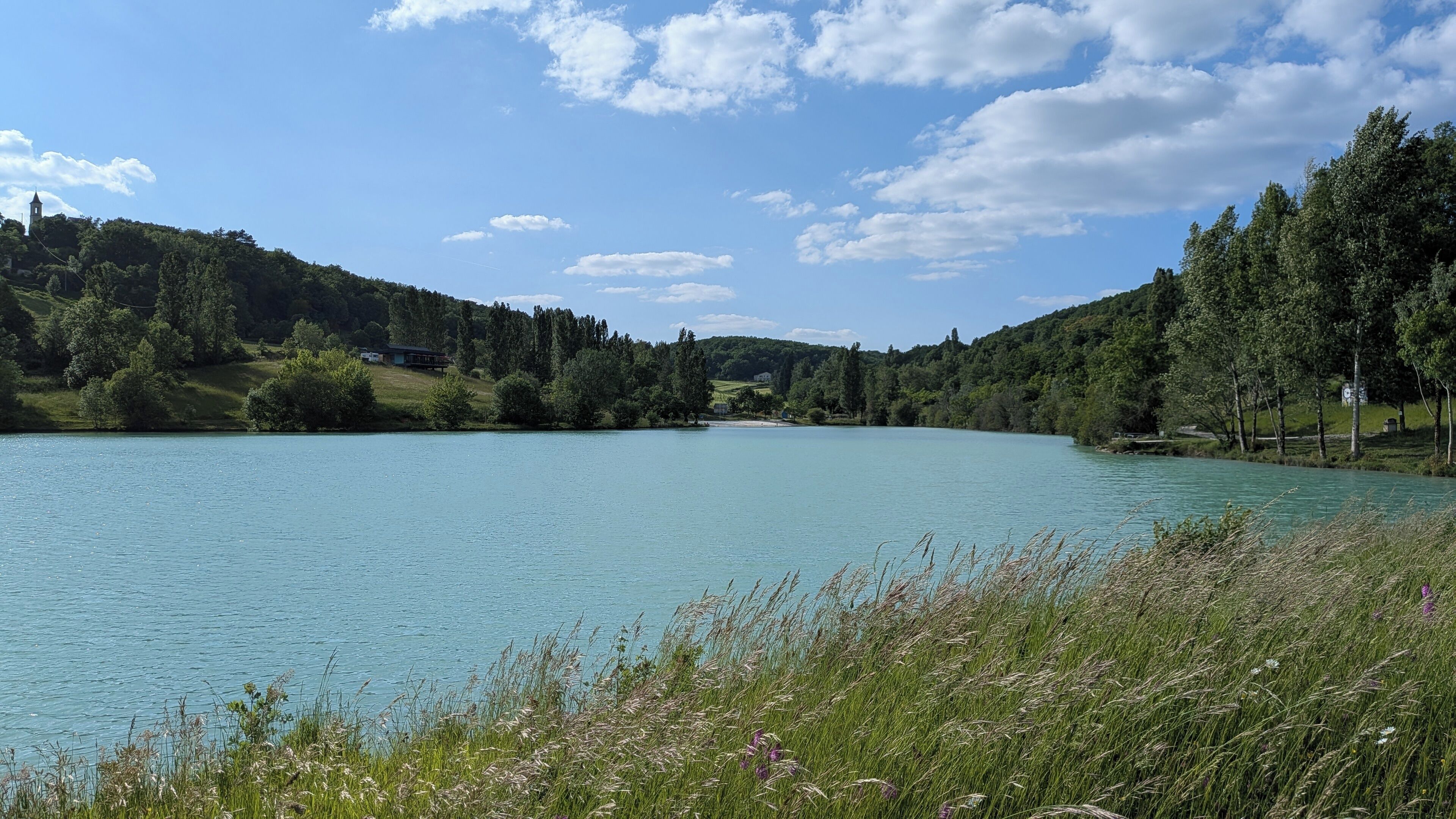 A serene lake surrounded by lush greenery and hills.