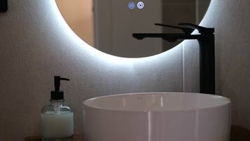 Un baño con lavamanos blanco, grifo negro y dispensador de jabón.