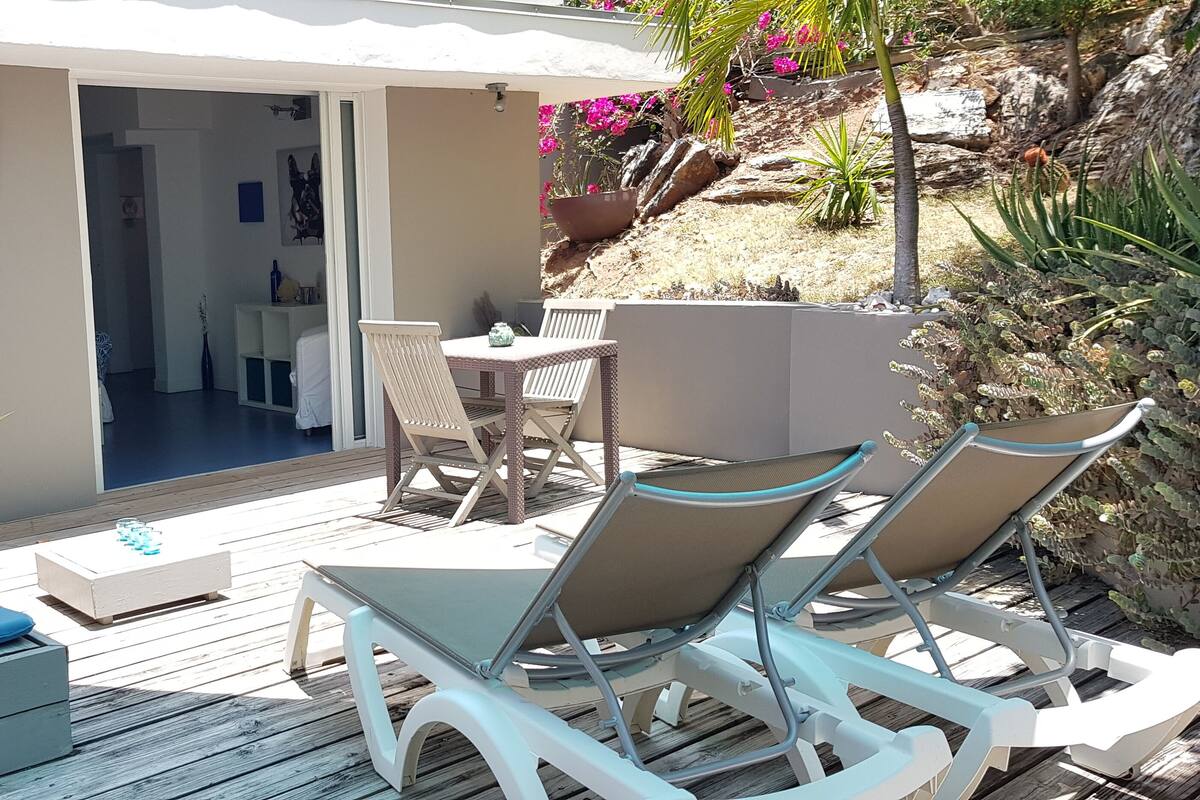 A sunlit patio with a dining table, chairs, and a small potted plant.