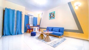 Ein modernes Wohnzimmer mit einem blauen Sofa, einem Couchtisch und einem Essbereich mit Stühlen und einem Tisch.