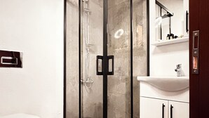 A modern bathroom with a glass-enclosed shower, a white sink, and a toilet. - Milestone Otel (Ayvalik)