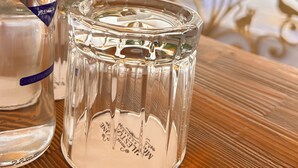 A bottle of Ulta Premium water and a clear glass with embossed text on a wooden surface. - Milestone Otel (Ayvalik)