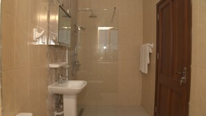 Une salle de bain moderne avec une douche à parois de verre, un lavabo blanc et une porte en bois.