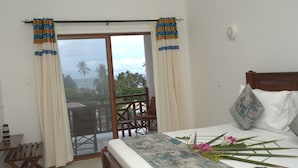 Une chambre à coucher avec un lit, une vue sur l’extérieur et un balcon avec des chaises.